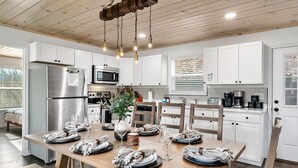 Una cocina moderna con armarios blancos, electrodomésticos de acero inoxidable y una mesa de comedor de madera para seis comensales.