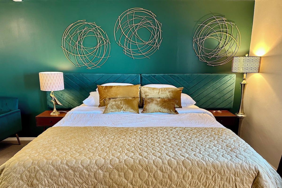 Ein Hotelzimmer mit einem Bett, einem Nachttisch, einer Lampe und dekorativen Wandbildern.