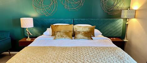 A hotel room with a bed, a nightstand, a lamp, and decorative wall art.