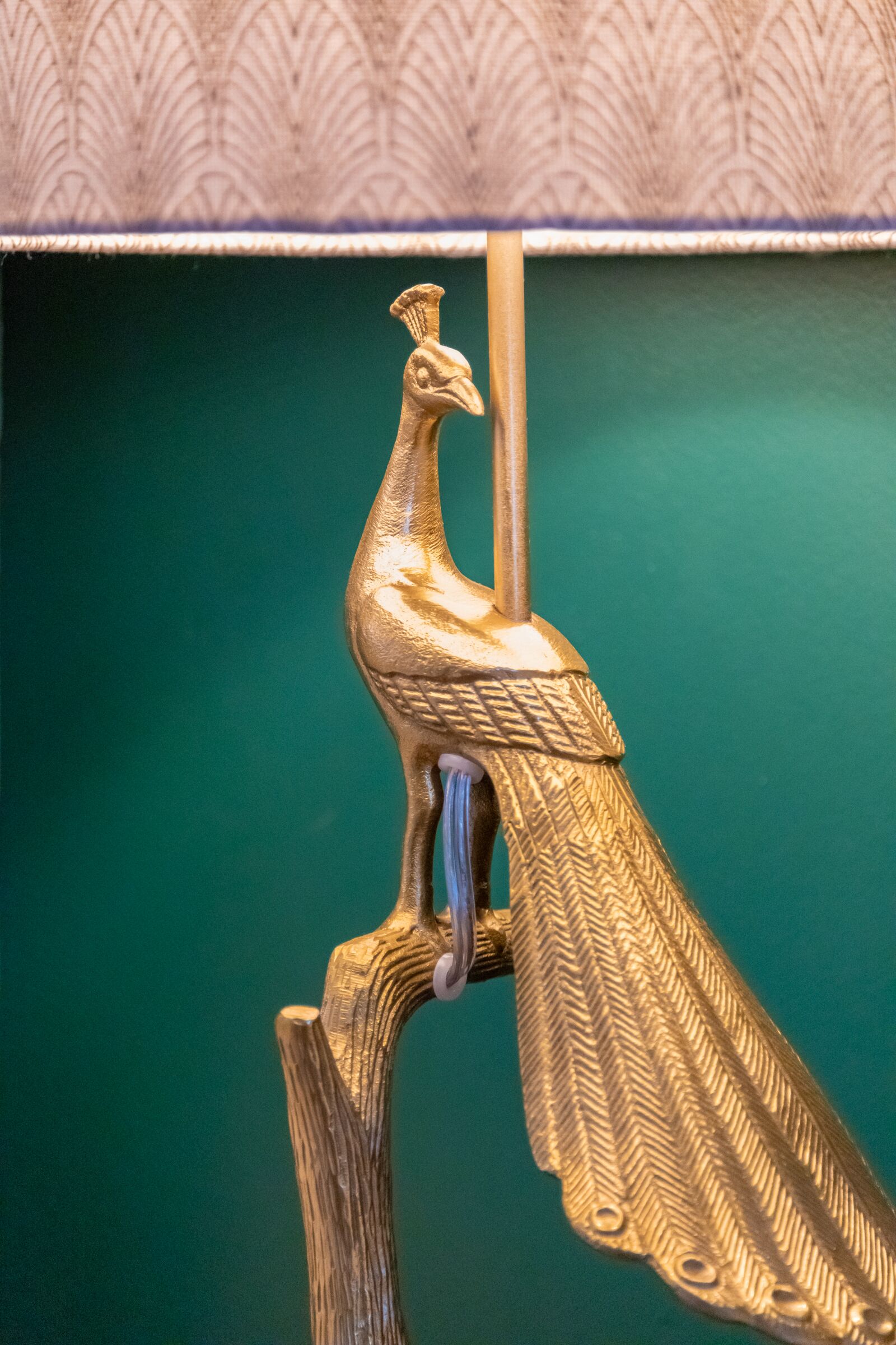 Una escultura de un pavo real dorado sobre un soporte de madera.