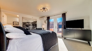Une chambre d’hôtel moderne dotée d’un grand lit, d’un téléviseur à écran plat, d’une commode et offrant une vue sur le paysage urbain par la fenêtre.