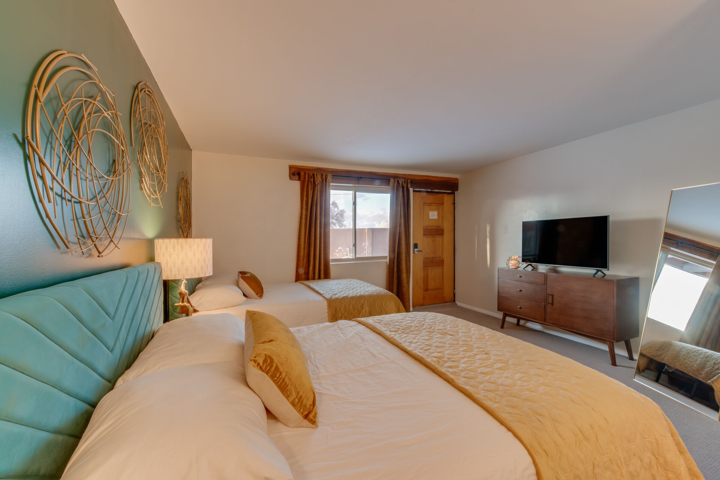 A hotel room with two beds, a TV, a dresser, and a large mirror.
