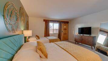 A hotel room with two beds, a TV, a dresser, and a large mirror.