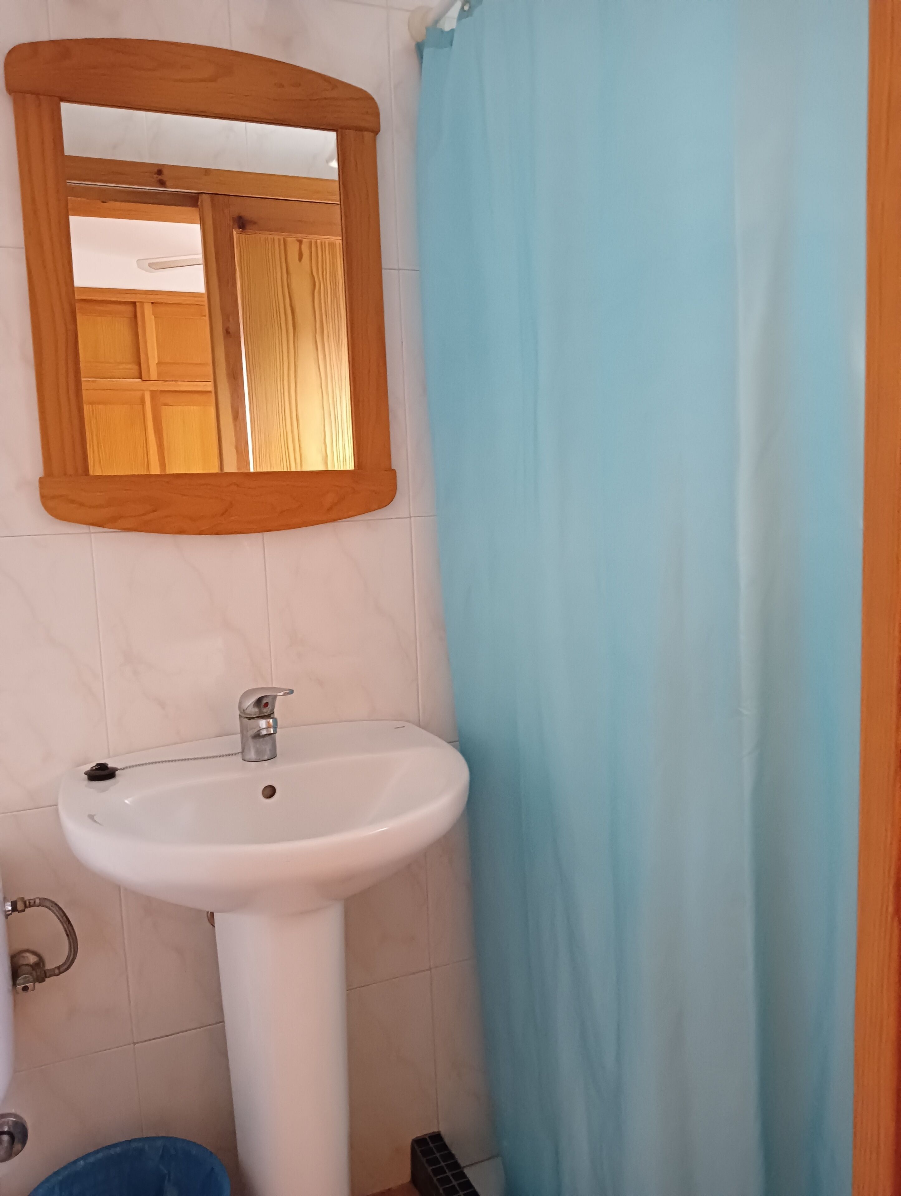A bathroom with a white sink, a wooden-framed mirror, and a blue shower curtain.