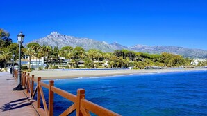 A coastal walkway with a wooden railing, leading to a beach with a mountain backdrop. - Magnificent recently built villa Pax 12 sea view Golden Mile Marbella (Marbella)