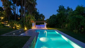 A swimming pool with a stone border, surrounded by lush greenery and palm trees. - Magnificent recently built villa Pax 12 sea view Golden Mile Marbella (Marbella)