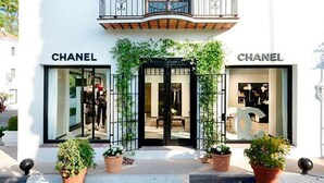 A white building with 'CHANEL' signage at the ground level, a balcony with 'LM' logos, and a sign reading 'Lis Melgarejo Arquitectura'. - Magnificent recently built villa Pax 12 sea view Golden Mile Marbella (Marbella)