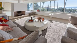 A modern living room with a large window, a fireplace, and a round coffee table. - Magnificent recently built villa Pax 12 sea view Golden Mile Marbella (Marbella)