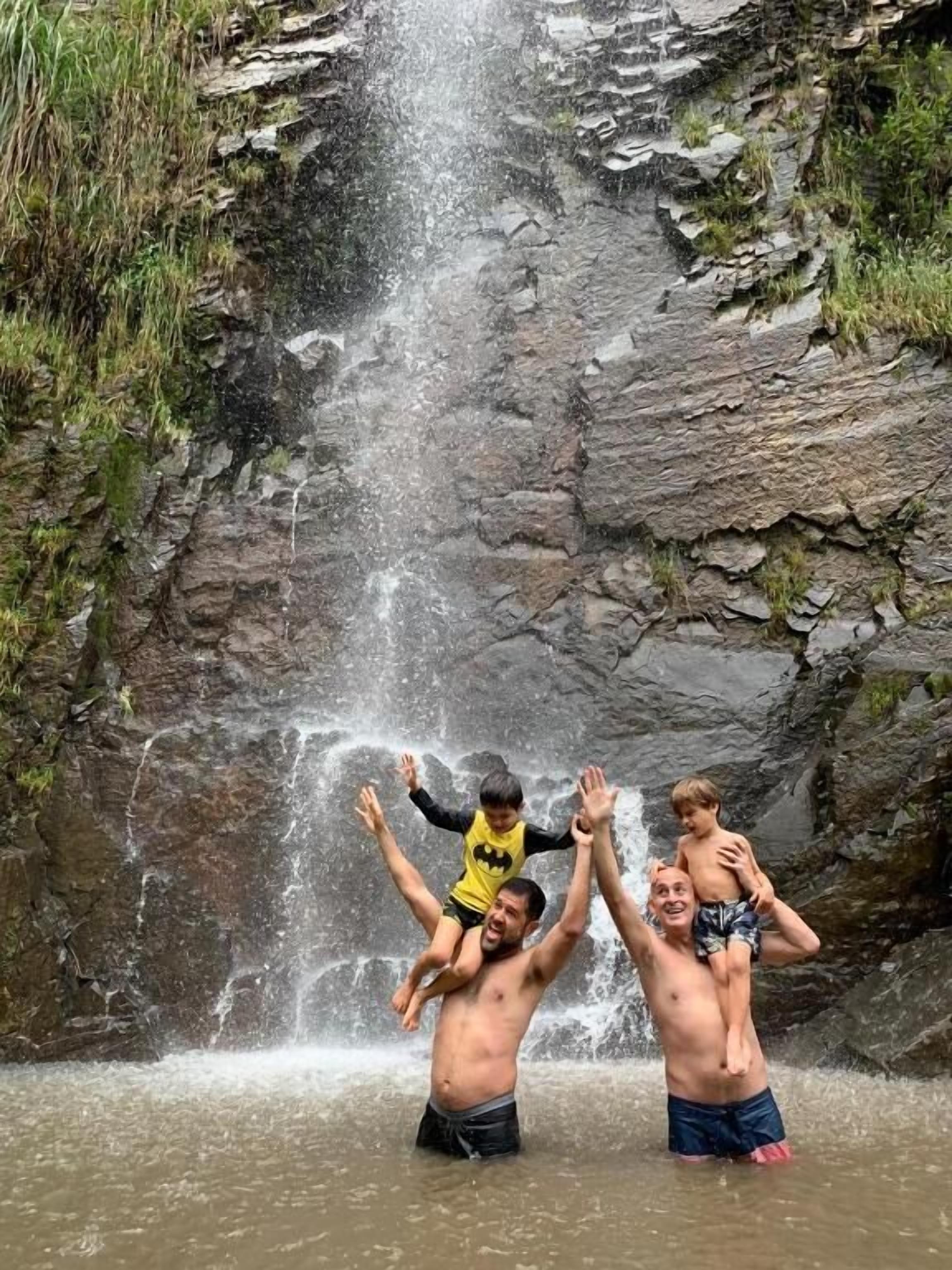 Una cascada con tres personas de pie en el agua.