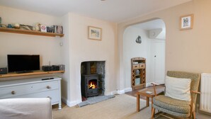 A living room with a fireplace, a television, and a cozy seating area. - 30 Sherborne Lane (Lyme Regis)