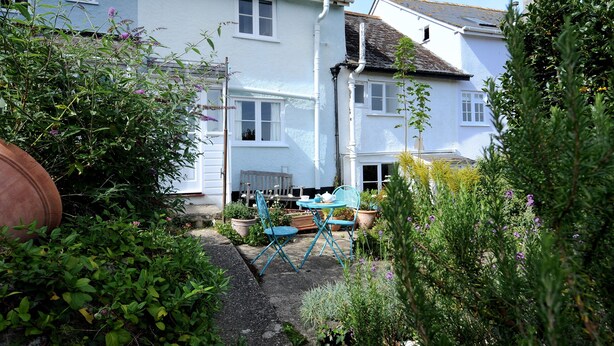 A white house with a garden, a blue chair, and a small table. - 30 Sherborne Lane (Lyme Regis)