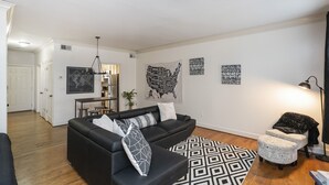 A modern living room with a black sofa, patterned rug, and wall art. - "The Traveller" 2bd Townhome off WEST END! 8 min ->DT! (Nashville)
