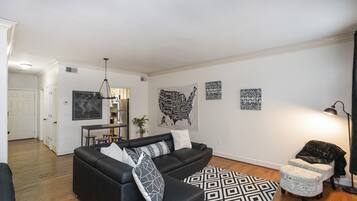 A modern living room with a black sofa, patterned rug, and wall art.