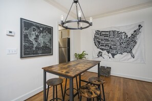 Ruokailutilassa on puinen pöytä ja jakkarat, maailmankartta, Yhdysvaltojen kartta ja moderni kattokruunu.