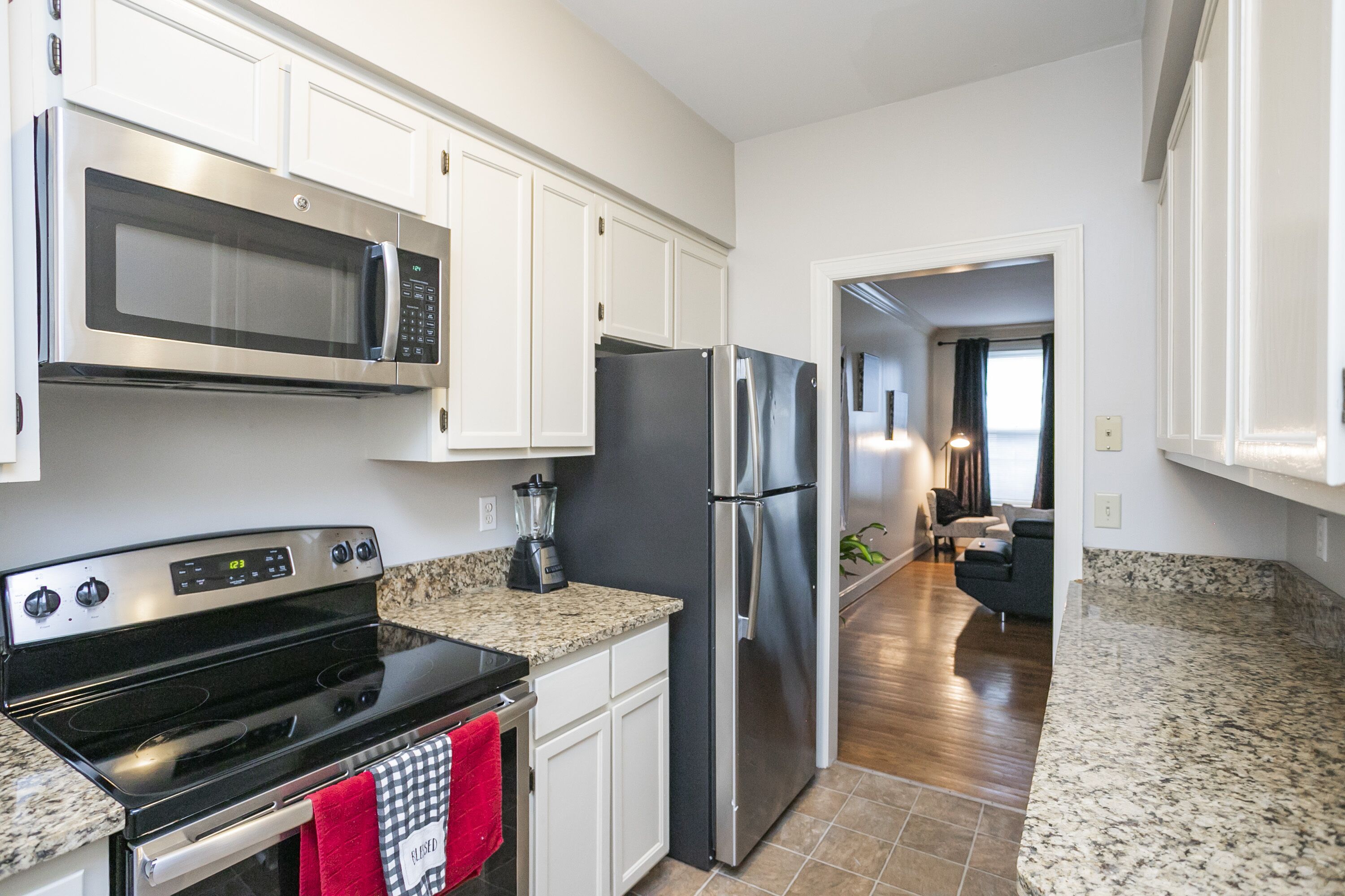 A modern kitchen with stainless steel appliances, white cabinetry, and granite countertops.