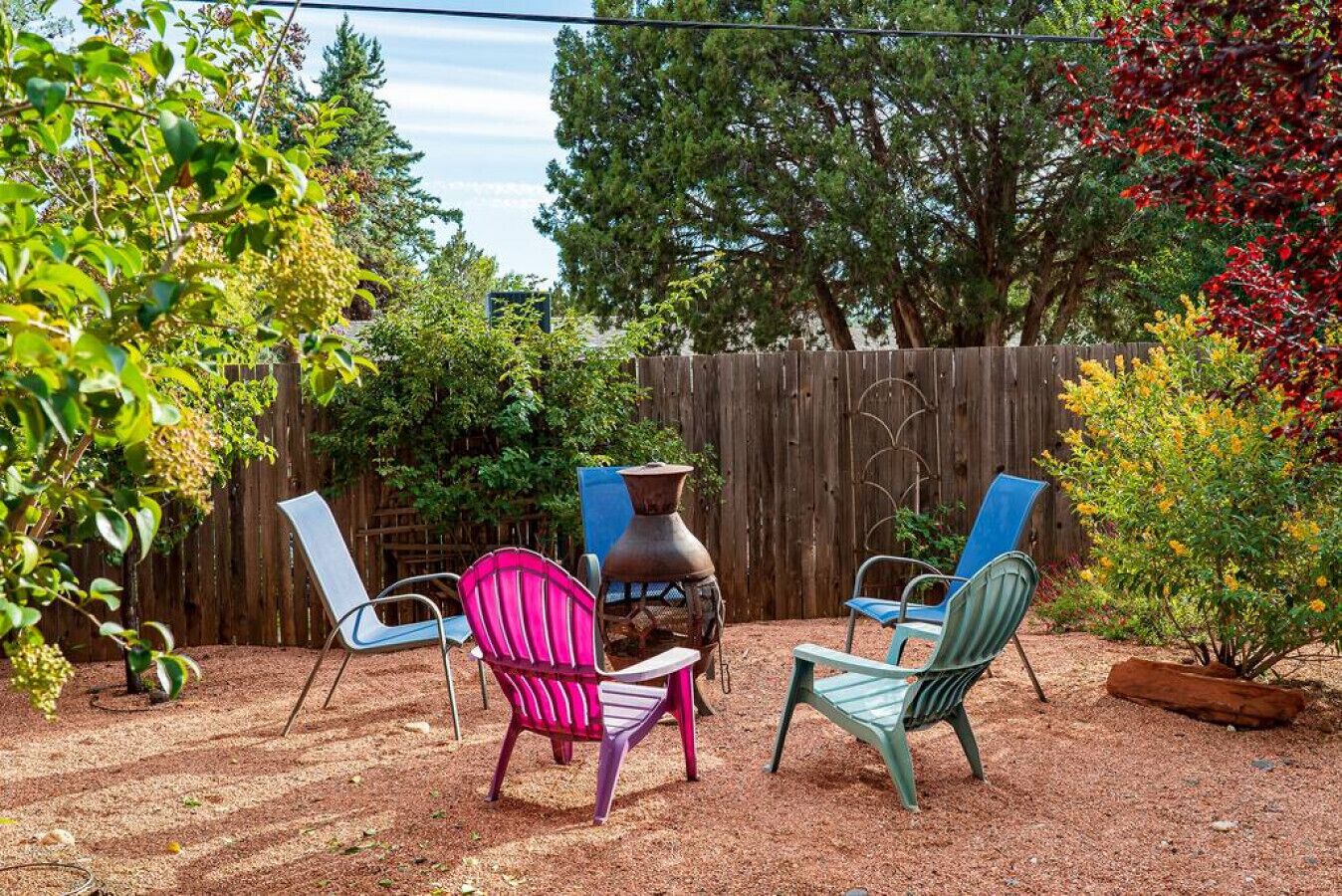 Un espace extérieur aménagé en patio, comprenant deux chaises en métal, une table en métal et une sculpture décorative en métal.