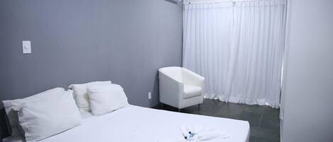 Une chambre d’hôtel avec un lit, une chaise et une salle de bain avec un rideau.