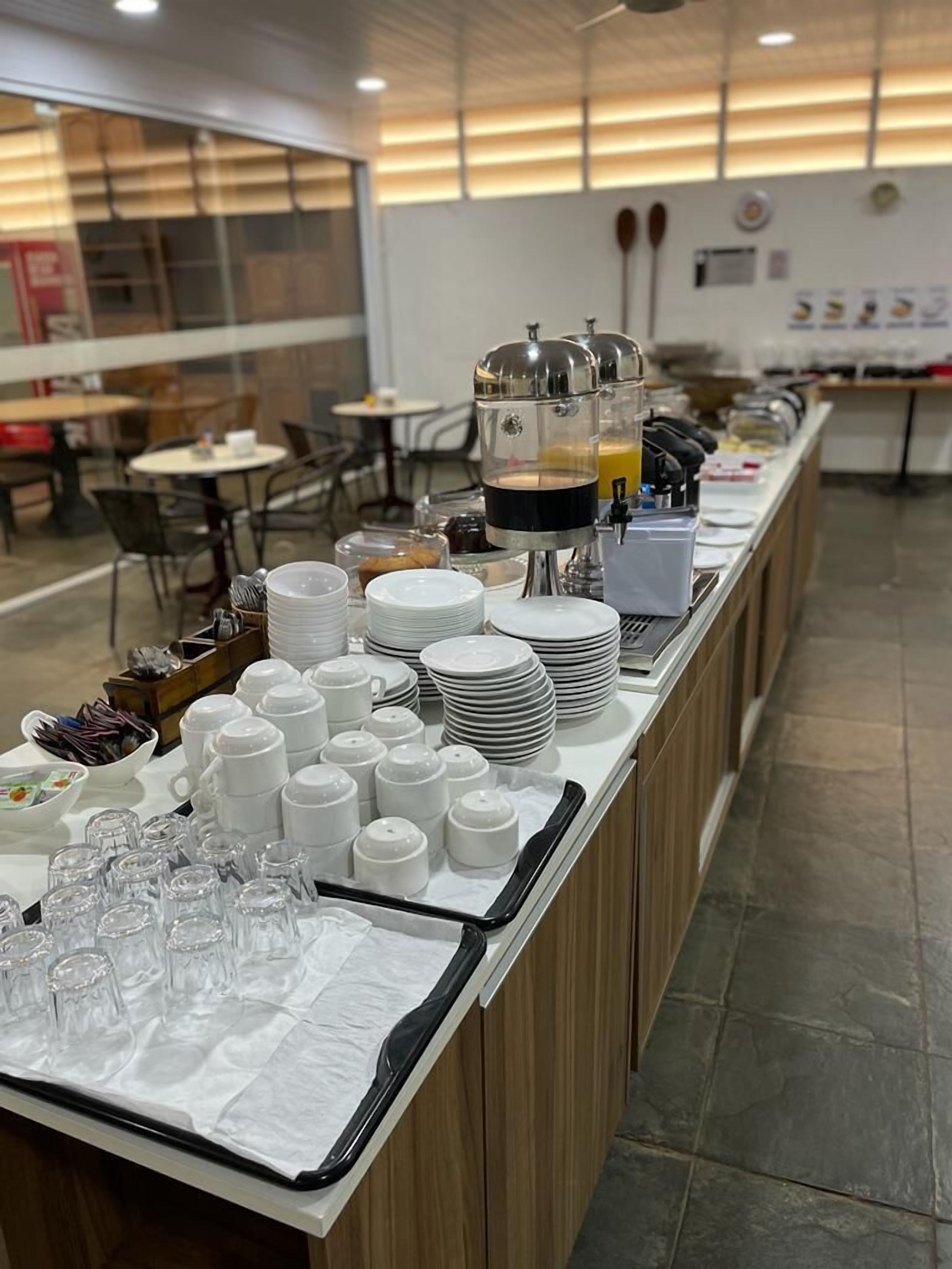 A buffet setup with various dishes, plates, and cups.