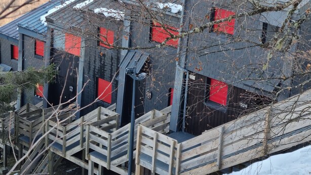 A multi-story building with red shutters, wooden staircases, and a metal fence.