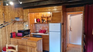 A compact kitchen with wooden cabinets, a refrigerator, a microwave, and a toaster.