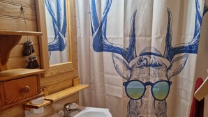 A bathroom with wooden fixtures, a sink, a mirror, and a shower curtain with a deer design.