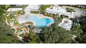 An aerial view of a resort with a large swimming pool, landscaped areas, and a building with a flat roof. - Your house 20 minutes from Disney, with pool area (Davenport)