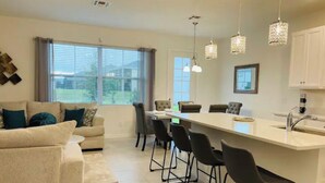 A modern kitchen with a central island, bar stools, and pendant lighting. - Your house 20 minutes from Disney, with pool area (Davenport)