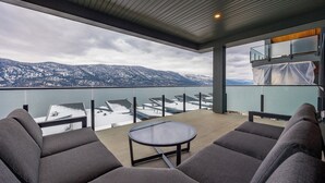 Ein Balkon mit Blick auf schneebedeckte Berge, einem Glastisch und grauen Polstermöbeln.