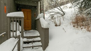 A wooden cabin with a snow-covered entrance and steps leading up to a door. - Wonderful Condo in the Aspens, Summer Pool & Tennis Courts (Vail)
