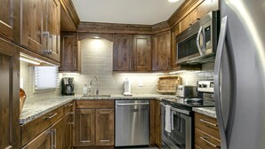 A modern kitchen with wooden cabinets, stainless steel appliances, and a tiled backsplash. - Wonderful Condo in the Aspens, Summer Pool & Tennis Courts (Vail)