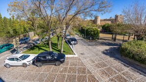 A parking area with cars, a stone pathway, and a historic building in the background.