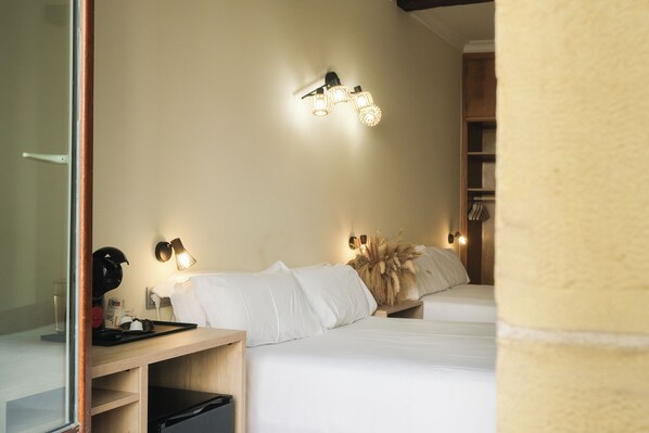 A hotel room with two beds, a bedside table, a lamp, and a wall-mounted light fixture. - Pensión Artea (San Sebastián)