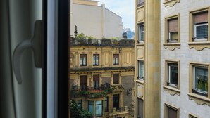 Vista d'un edifici amb nombroses finestres i balcons, visible a través d'un marc de finestra.