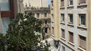 Vistes d'un carrer amb edificis, un arbre i un cel clar.