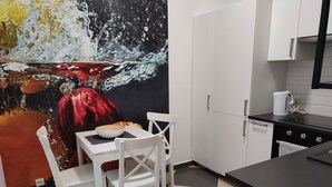 A modern kitchen with white cabinets, a black countertop, and a checkered floor.