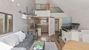 Eine moderne Wohnung mit Wohnzimmer, Küche und einem Schlafzimmer im oberen Bereich.