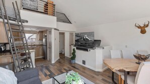 Eine moderne Wohnung mit Schlafgalerie, einer Küche, einem Essbereich und einem Wohnzimmer.