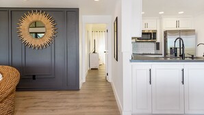 Una cocina moderna con alacenas blancas, microondas integrado y refrigerador de acero inoxidable.