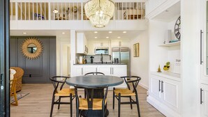 Una cocina moderna con armarios blancos, una isla central y una lámpara de araña.