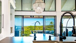Una cocina moderna con una isla grande, un lavamanos de acero inoxidable y vistas al exterior a través de amplios ventanales.