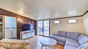 Una sala de estar moderna con un sofá, una televisión, una mesa de comedor y una silla de mimbre.
