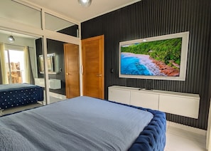 A bedroom with a bed, a TV, a wardrobe, and a mirror. - Villa los paulas THE BEST ROOFTOP with jacuzzi(NEW) (Punta Cana)