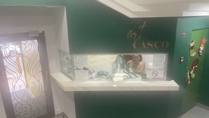 Un comptoir d’accueil avec un mur vert et une enseigne indiquant « HÔTEL CASCO ».