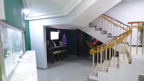 Un vaste espace de vie comprenant un escalier, une table à manger et un téléviseur.