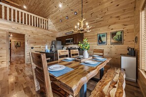 Een houten cabin met een eethoek, keuken en een wenteltrap.