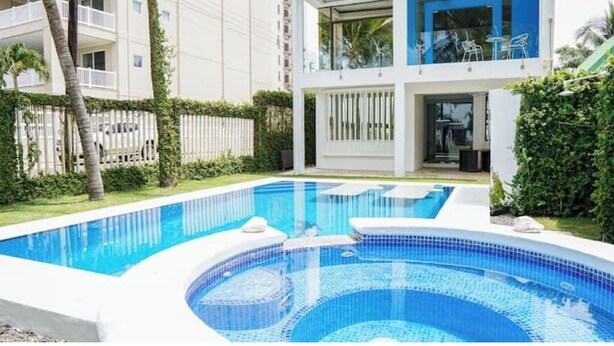 A modern hotel with a swimming pool, a covered patio, and a view of the surrounding buildings. - Oceanfront Pool Paradise Villa (Provincia de Puntarenas)