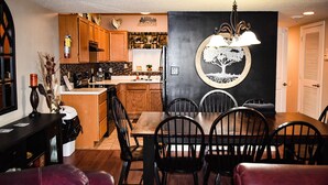 Ein Essbereich mit einem Holztisch und Stühlen, einer Chandelier und einer Wand mit einem Baum-Wandgemälde.