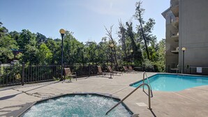 Ein Poolbereich mit Liegestühlen und einem Whirlpool, umgeben von Bäumen und einem Gebäude.