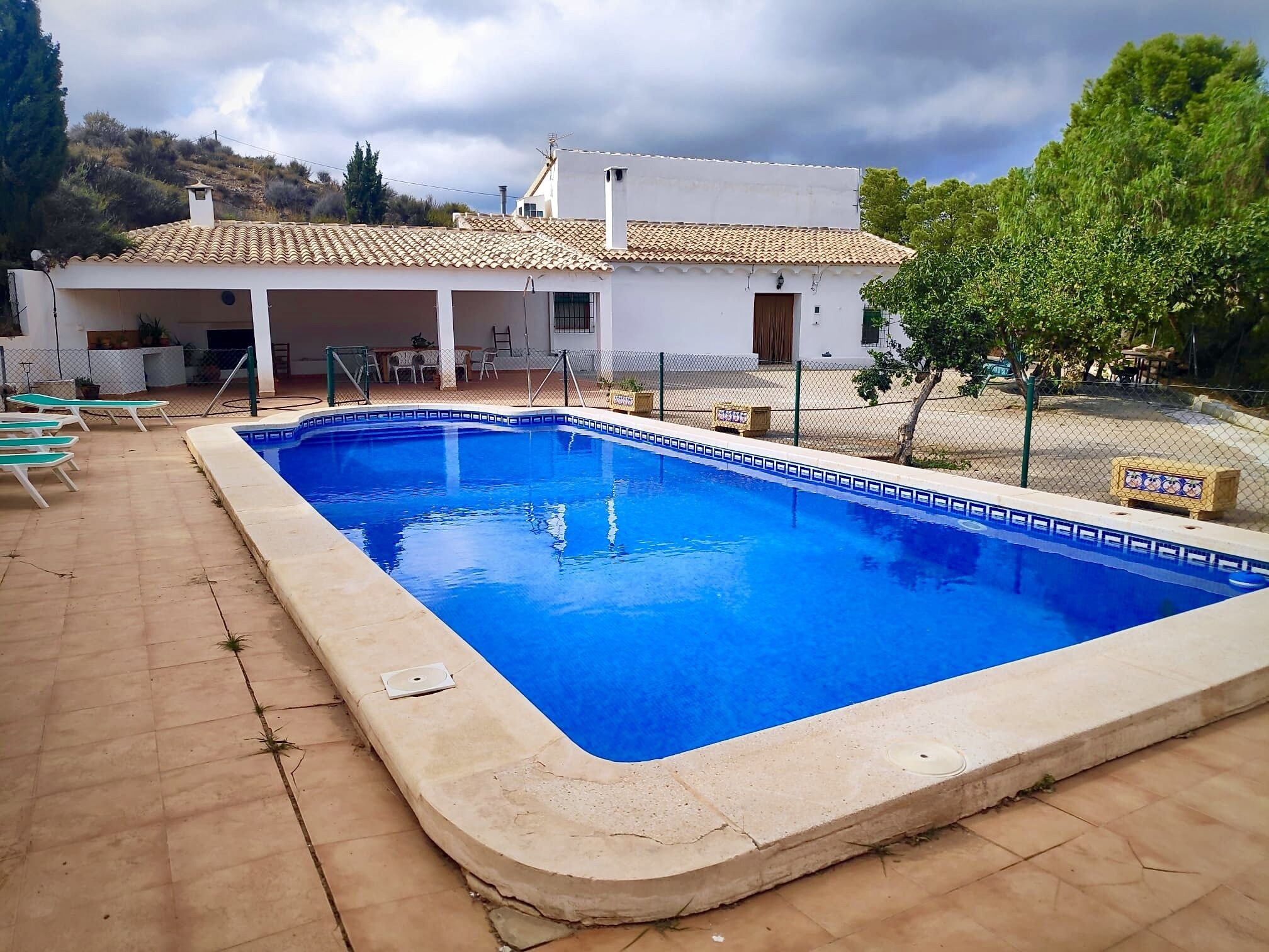 A rectangular swimming pool with a tiled edge, surrounded by a tiled deck.