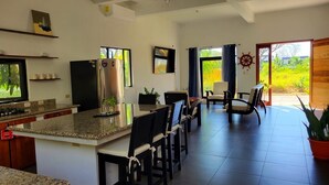Una cocina moderna con encimeras de granito, un refrigerador de acero inoxidable y un comedor con sillas y una mesa.